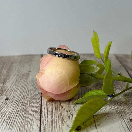 Ring on a pink flower with green leaves on a wooden surface