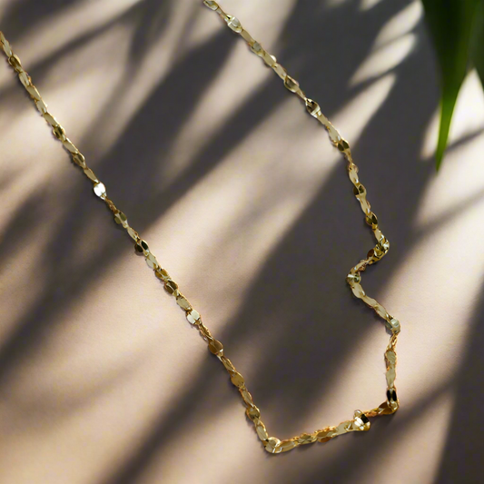 Gold chain necklace on a light gray fabric background