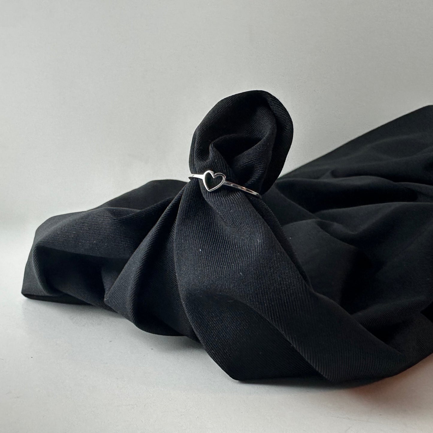 Black fabric with a heart-shaped ring on a white background
