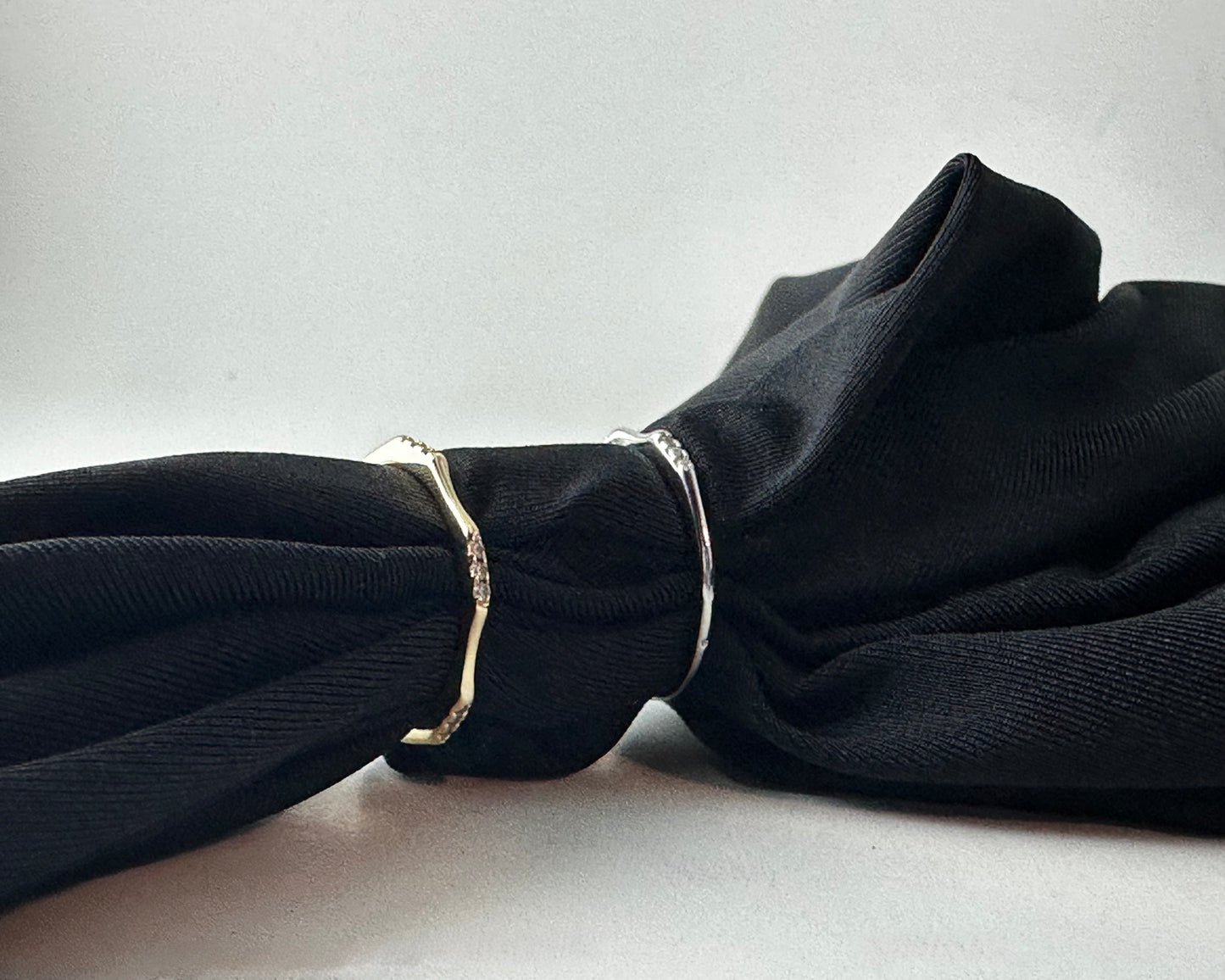 A gold and silver ring on a black fabric background