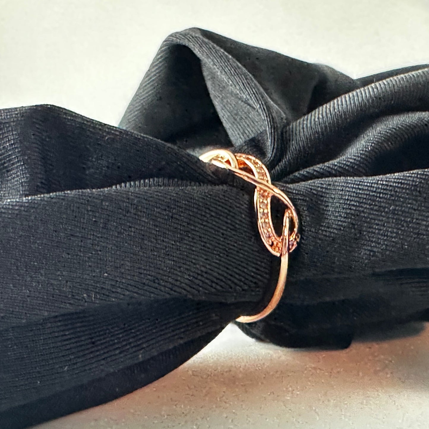 Gold infinity ring on a black fabric background