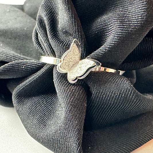 Butterfly-shaped silver ring on a black fabric background