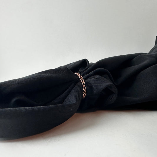 Black fabric with a rose gold heart ring on a white background