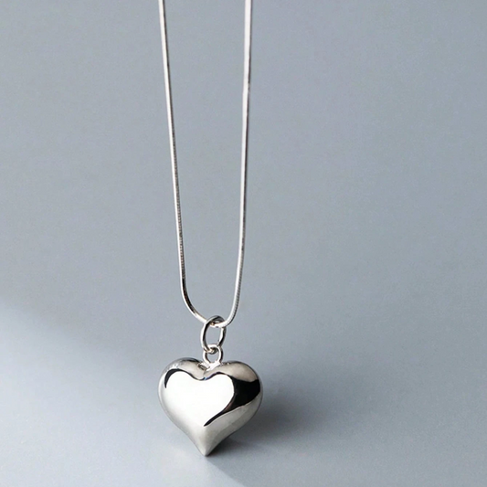 Silver heart-shaped pendant on a chain against a light gray background
